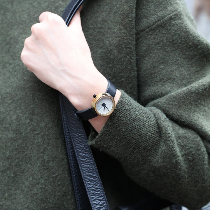 A Modern Watch With A Gold Case And Black Italian Leather Strap On A Woman's Wrist