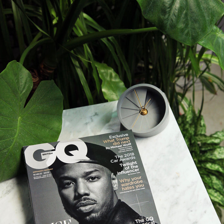 Table clock next to GQ magazine with plants 