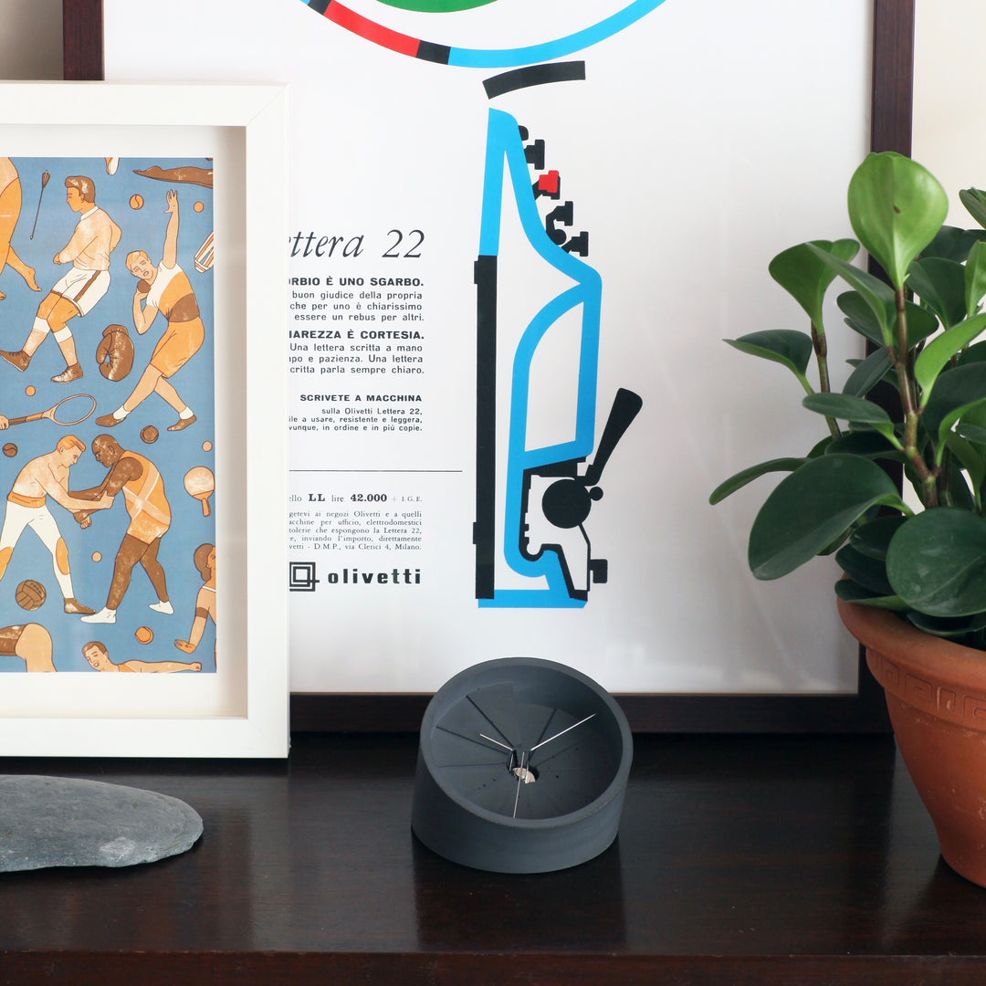 Clock on side table with paintings and plant