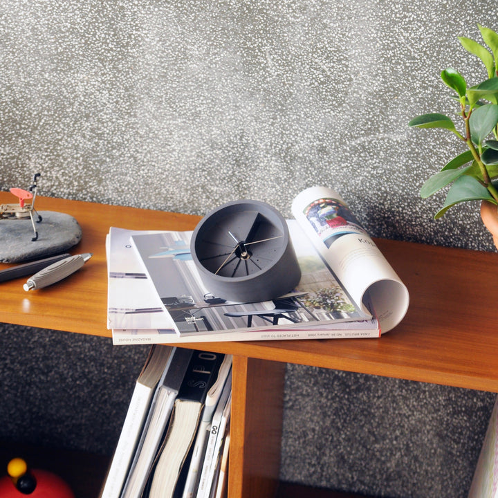 Clock on magazine with concrete accessories surrounding it