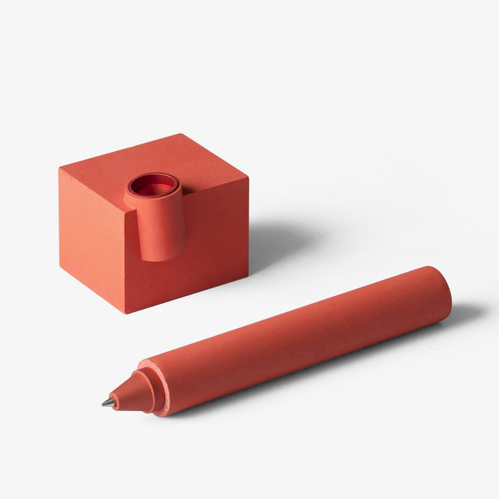 Red desk pen and holder laying separate 