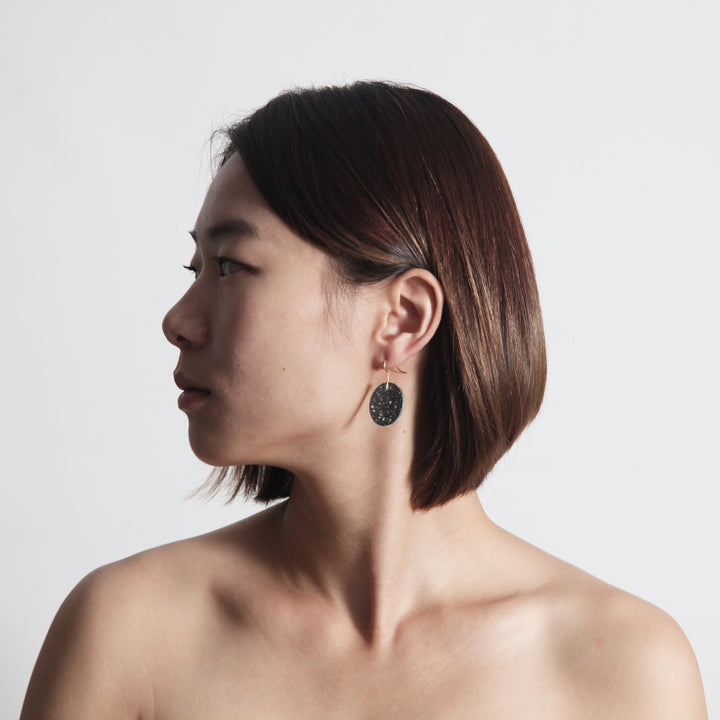 Woman Model Wearing 22STUDIO Concrete Circle Earrings In Dark Gray