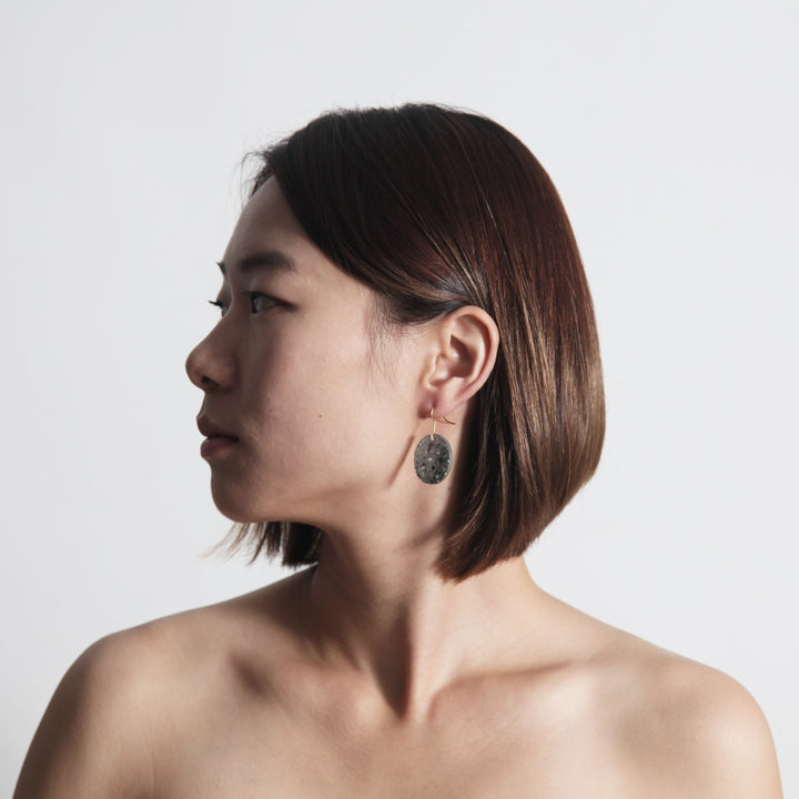 Woman Model Wearing 22STUDIO Concrete Circle Earrings In Light Gray