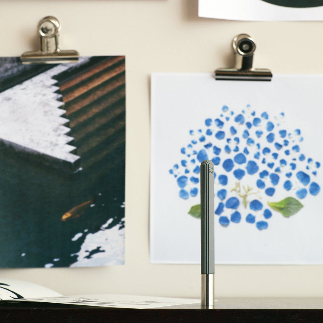 A Concrete Pen by 22STUDIO Resting on a Table in Front of Paintings